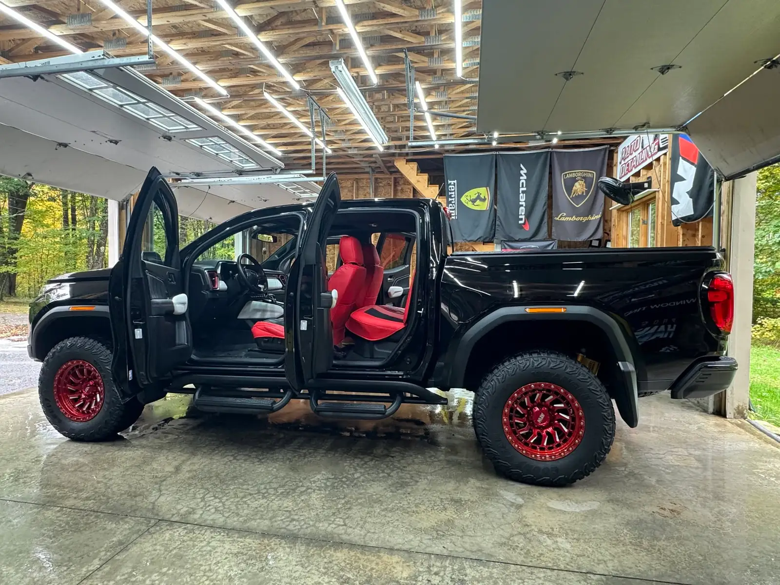 GMC Canyon AT4X with its doors open in the shop, red seats inside