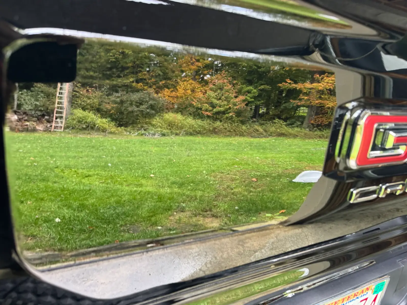 Fall trees reflected in the black GMC Canyon's finished paint