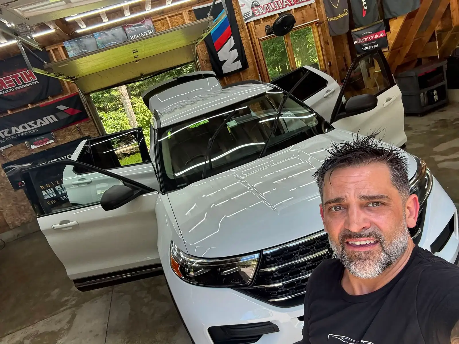 Jason in his shop with a white Ford Explorer, its doors open