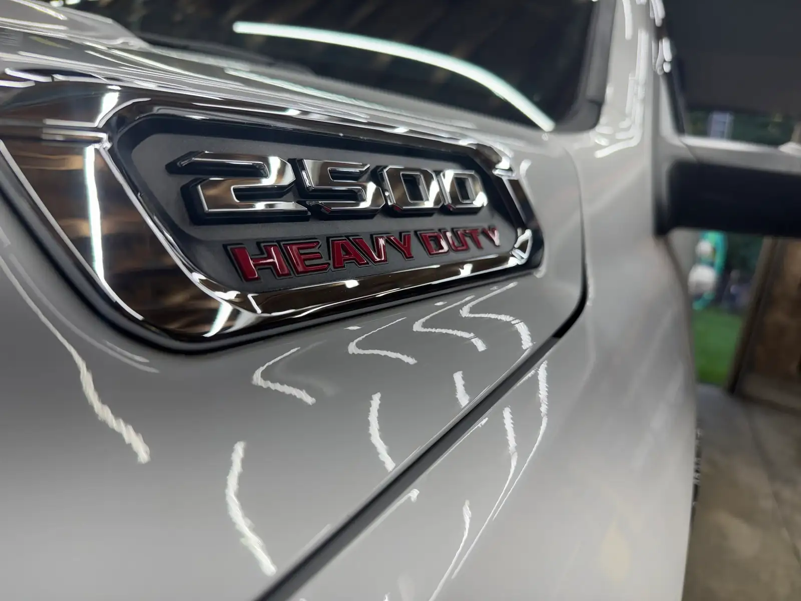 Ram 2500 Heavy Duty badge, clean, with the shop lights reflected in the white paint